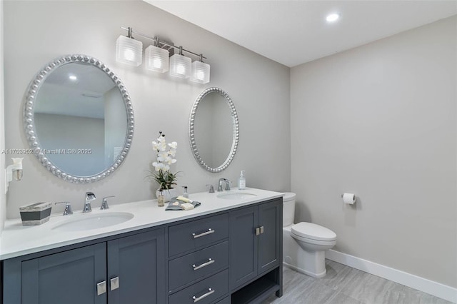 bathroom featuring baseboards, a sink, toilet, and double vanity