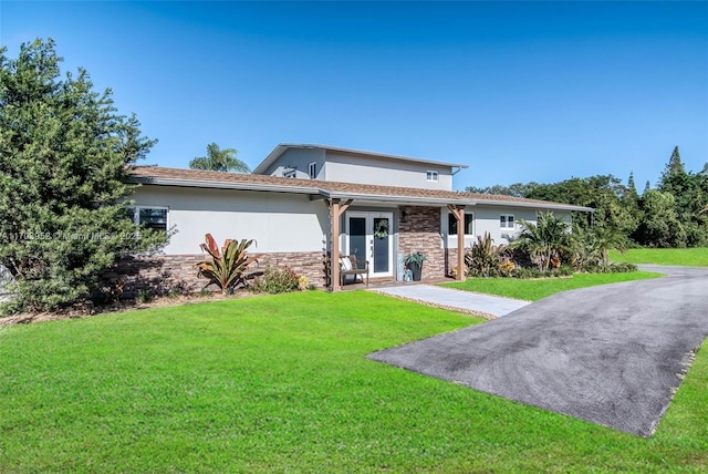 view of front of house with stone siding, a front lawn, and stucco siding