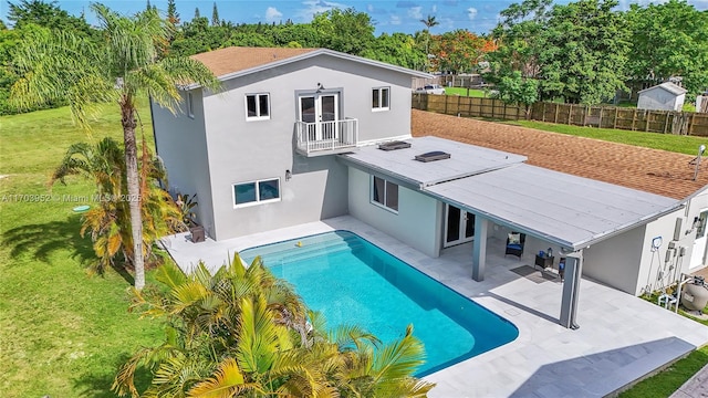 rear view of house with a patio, a balcony, fence, a yard, and stucco siding