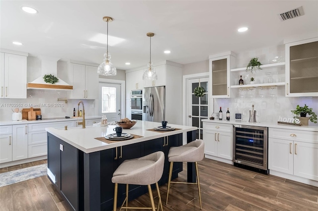 kitchen featuring visible vents, wine cooler, appliances with stainless steel finishes, light countertops, and premium range hood
