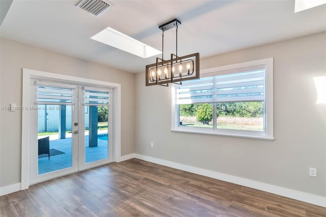 empty room with dark hardwood / wood-style floors, a healthy amount of sunlight, a skylight, and french doors