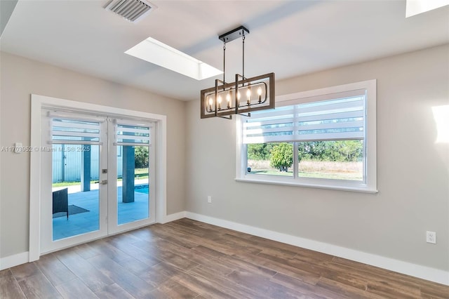 empty room with dark wood-style floors, visible vents, and a healthy amount of sunlight