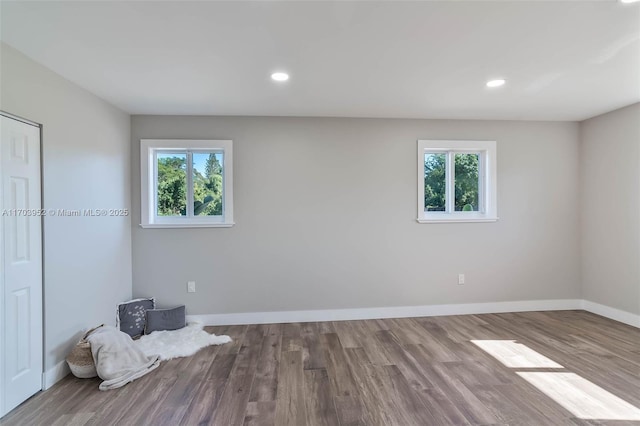 empty room with wood finished floors, a wealth of natural light, and baseboards