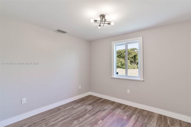 spare room with hardwood / wood-style floors and a notable chandelier