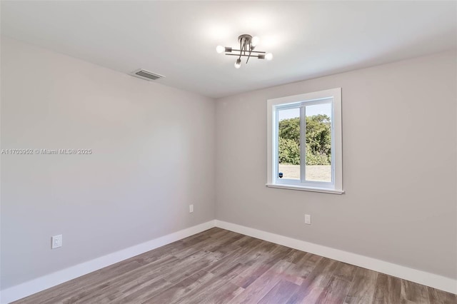 empty room with visible vents, baseboards, and wood finished floors