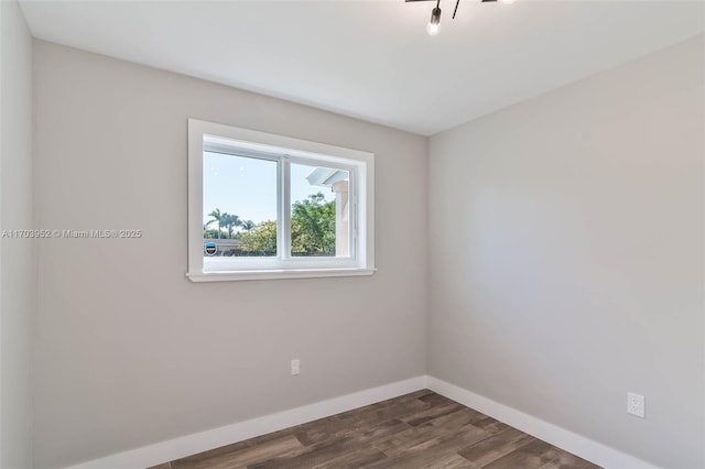 spare room with dark wood-style floors and baseboards