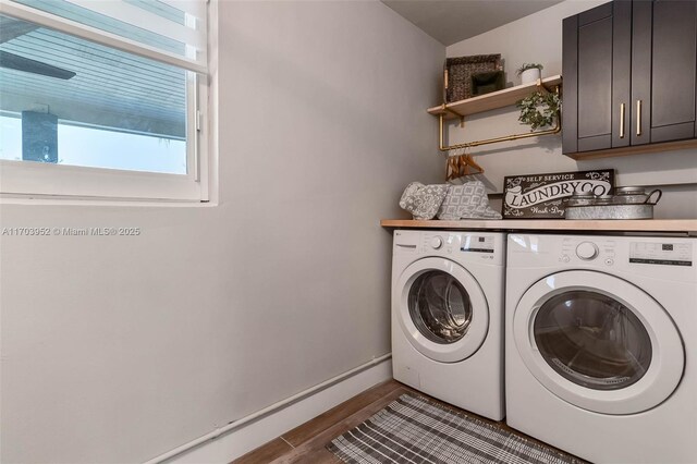 clothes washing area with cabinets, dark hardwood / wood-style flooring, and washer and clothes dryer