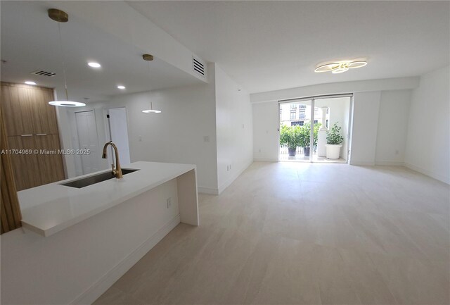 kitchen with kitchen peninsula, pendant lighting, sink, white cabinets, and stainless steel appliances