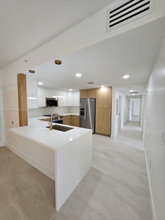 kitchen with sink, white cabinets, hanging light fixtures, kitchen peninsula, and stainless steel appliances