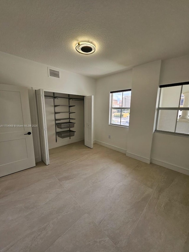 unfurnished bedroom featuring a textured ceiling and a closet