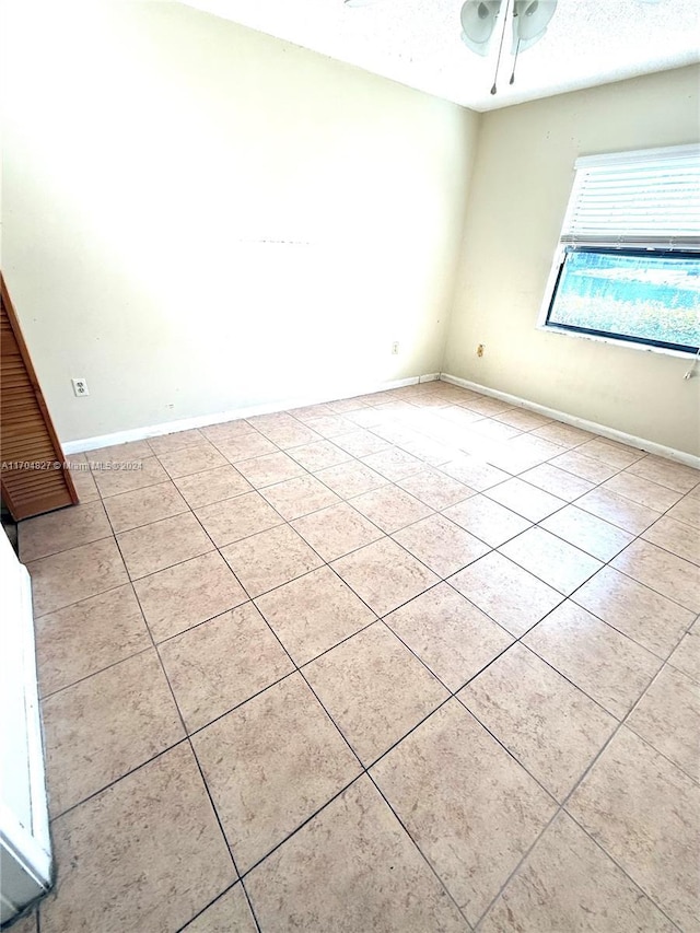 empty room featuring light tile patterned floors, a textured ceiling, and ceiling fan