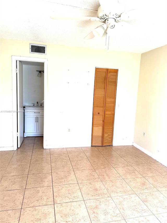 unfurnished bedroom with tile patterned flooring, ceiling fan, and a textured ceiling