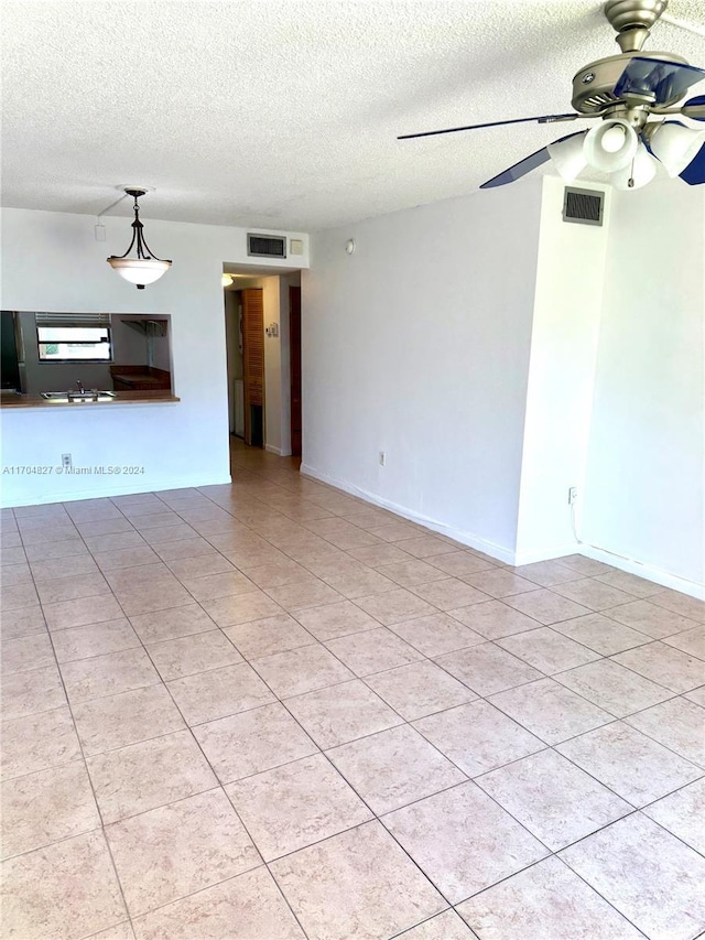 tiled spare room featuring ceiling fan and a textured ceiling