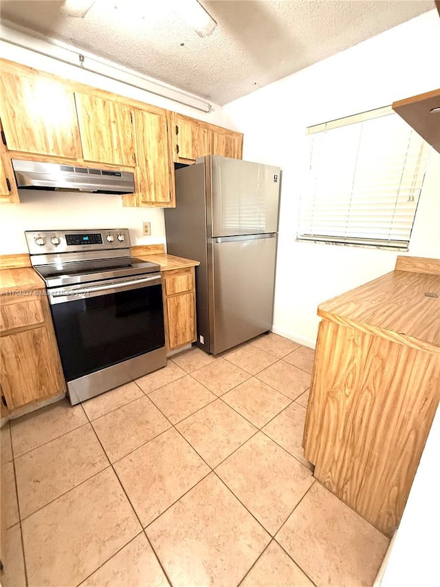 kitchen with appliances with stainless steel finishes, a textured ceiling, ventilation hood, and light tile patterned floors