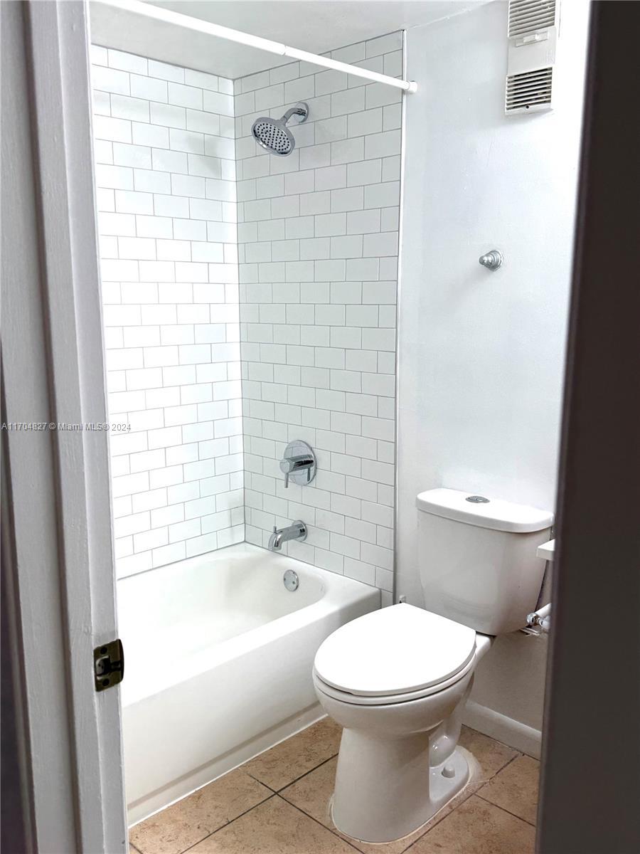 bathroom with tile patterned flooring, tiled shower / bath, and toilet