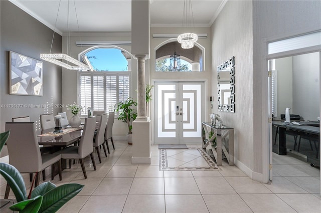 entryway featuring light tile patterned flooring, a towering ceiling, crown molding, and an inviting chandelier