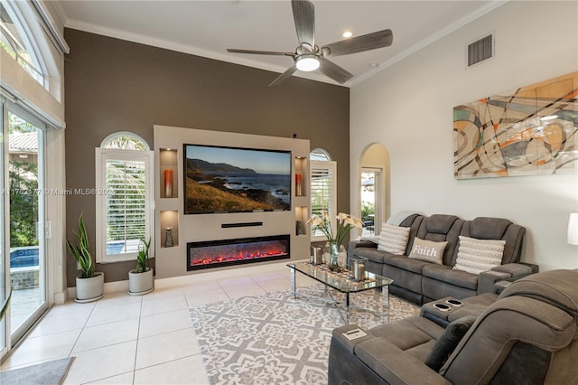 tiled living room with ceiling fan, a high ceiling, and ornamental molding