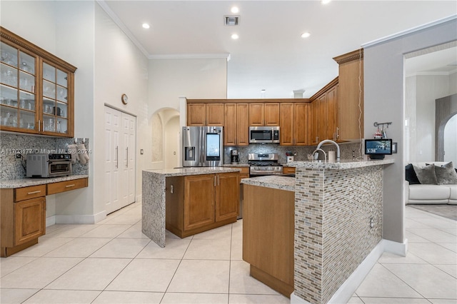 kitchen with light stone countertops, stainless steel appliances, and crown molding