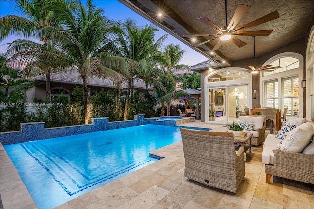 pool at dusk featuring an in ground hot tub, ceiling fan, a patio, and an outdoor hangout area