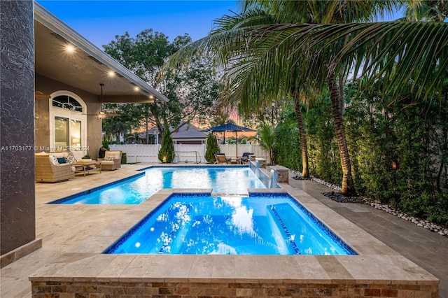 pool at dusk with a patio area and an outdoor hangout area