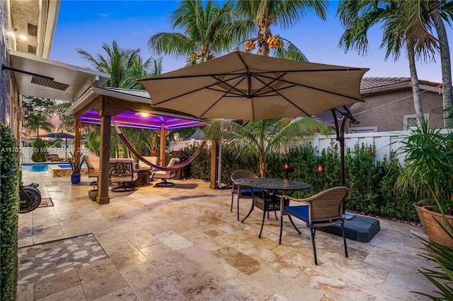 patio terrace at dusk with a fenced in pool