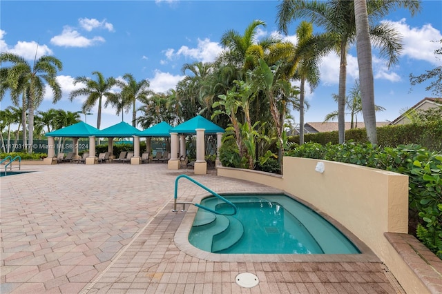 view of swimming pool featuring a hot tub and a patio area