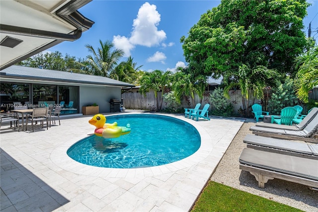 view of pool with grilling area and a patio