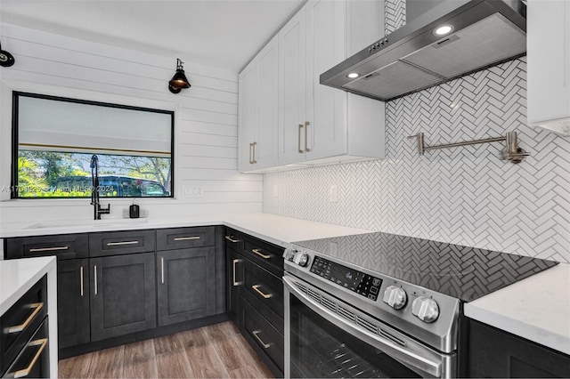 kitchen featuring white cabinets, stainless steel range with electric cooktop, dark hardwood / wood-style floors, and wall chimney range hood