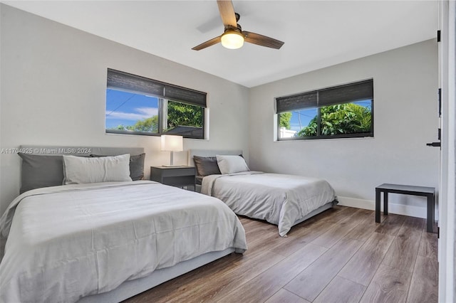 bedroom featuring hardwood / wood-style flooring, ceiling fan, and multiple windows