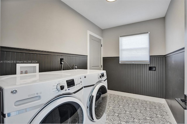 clothes washing area with wood walls and independent washer and dryer