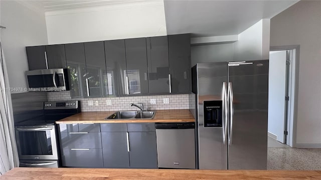 kitchen with sink, gray cabinets, ornamental molding, appliances with stainless steel finishes, and tasteful backsplash