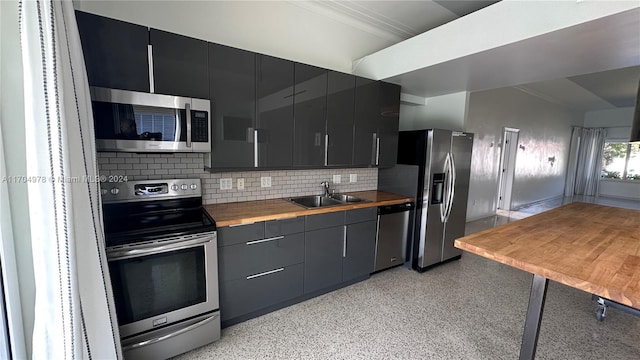 kitchen featuring wood counters, sink, ornamental molding, appliances with stainless steel finishes, and tasteful backsplash