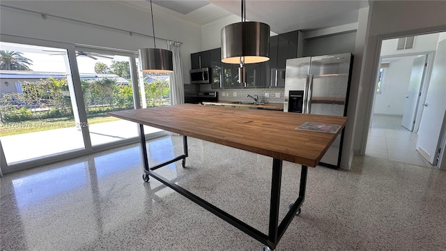 kitchen featuring sink, stainless steel appliances, hanging light fixtures, butcher block countertops, and decorative backsplash