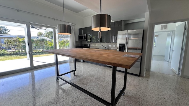 kitchen featuring sink, stainless steel appliances, tasteful backsplash, butcher block countertops, and decorative light fixtures