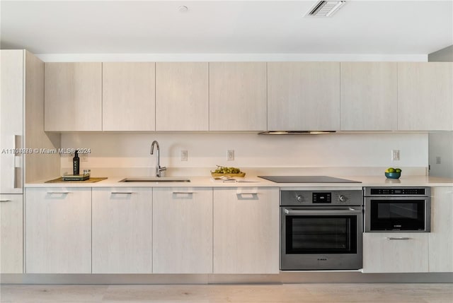 kitchen with oven, sink, and light brown cabinetry