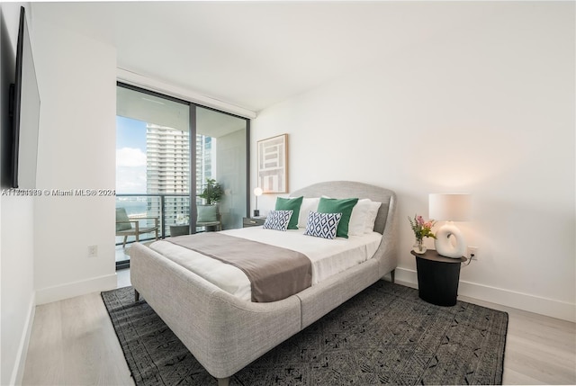 bedroom with light hardwood / wood-style flooring and a wall of windows