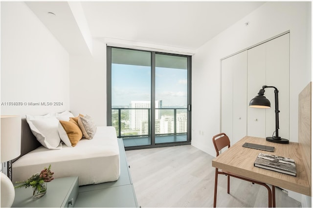 bedroom featuring expansive windows, access to exterior, a closet, and light hardwood / wood-style flooring