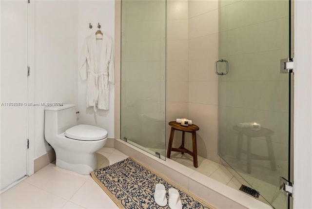 bathroom featuring tile patterned flooring, toilet, and a shower with door