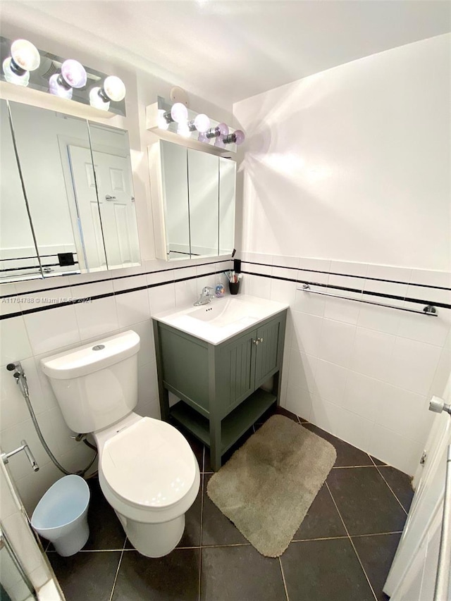 bathroom with tile patterned flooring, vanity, toilet, and tile walls