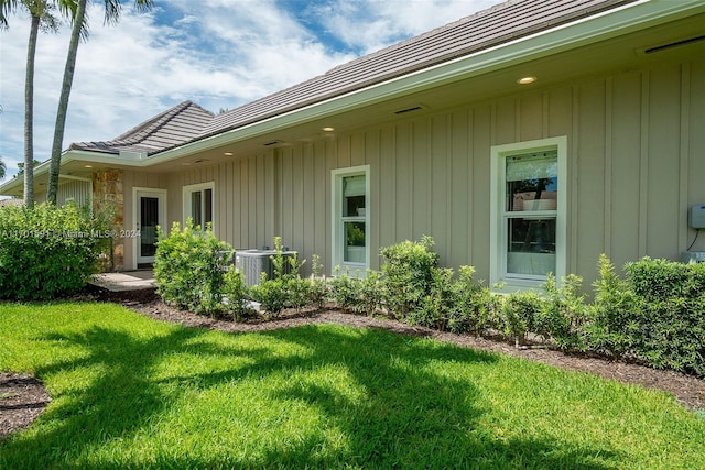 exterior space with central AC unit and a lawn