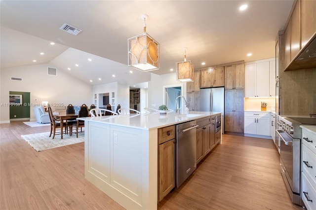 kitchen with sink, white cabinetry, a center island with sink, appliances with stainless steel finishes, and pendant lighting