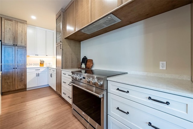 kitchen featuring white cabinetry, high end stove, and light hardwood / wood-style flooring