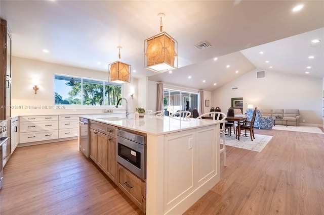 kitchen with sink, white cabinets, a large island, stainless steel appliances, and light wood-type flooring