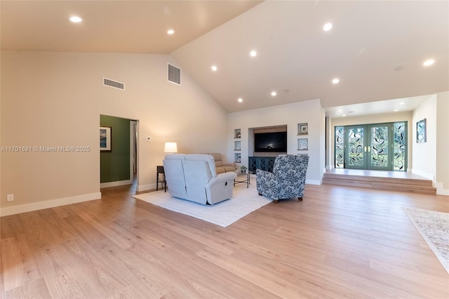 living room featuring light hardwood / wood-style flooring, high vaulted ceiling, and french doors