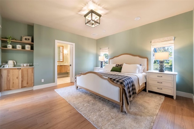 bedroom with connected bathroom and light hardwood / wood-style flooring