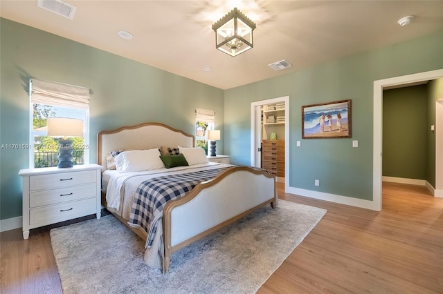 bedroom with a walk in closet and light wood-type flooring