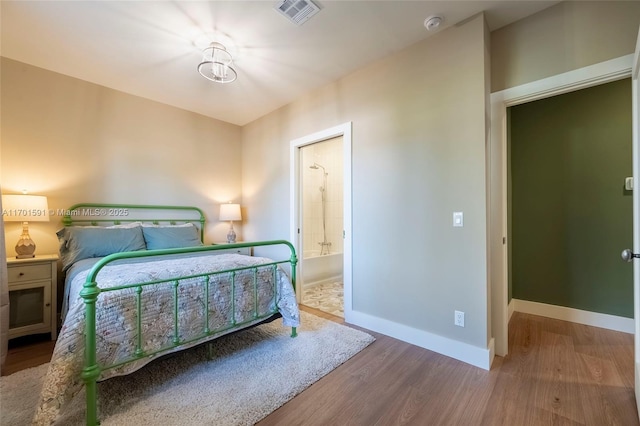 bedroom featuring ensuite bathroom and hardwood / wood-style floors