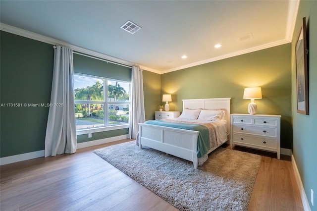 bedroom with crown molding and light hardwood / wood-style floors