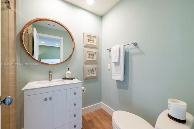 bathroom featuring wood-type flooring, toilet, and vanity