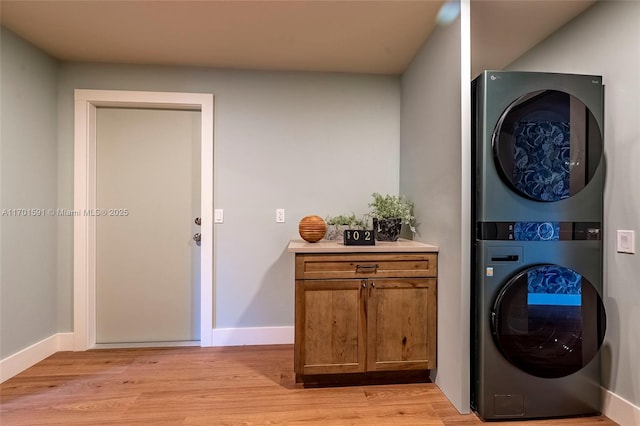 washroom with light wood-type flooring, cabinets, and stacked washer / dryer